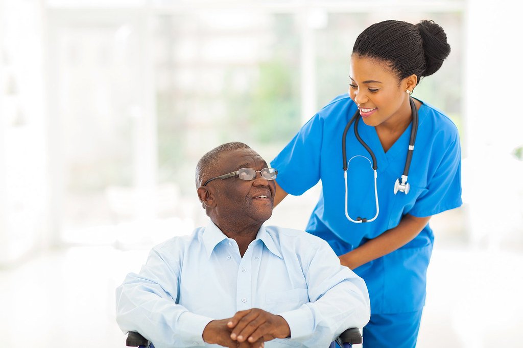 Caregiver smiling with a senior man in a wheelchair