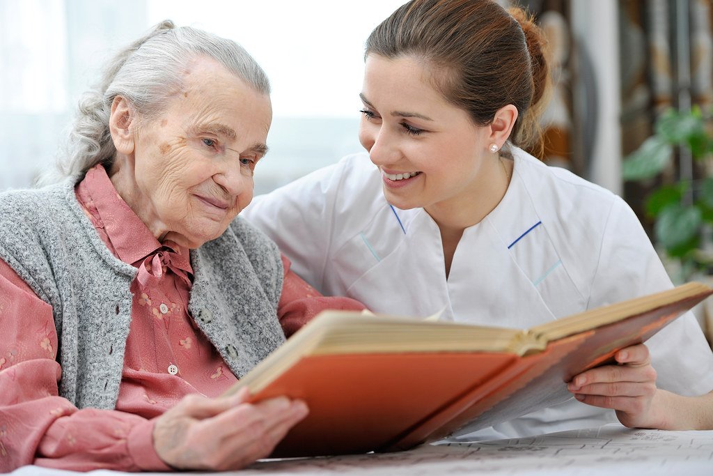 Caregiver reading a book with a senior woman