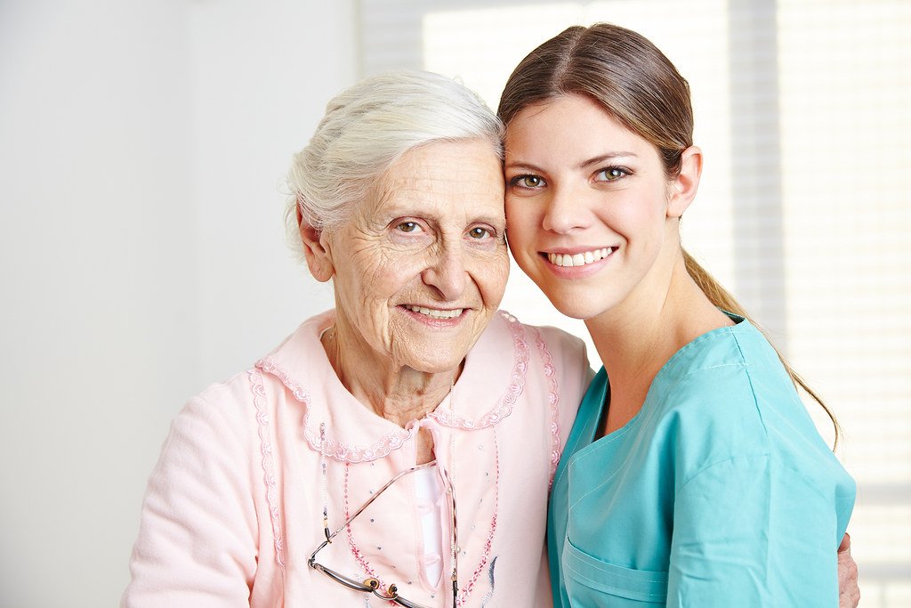 Smiling caregiver embracing a senior woman